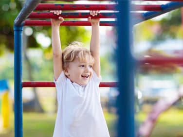 Kind hängt am Klettergerüst.